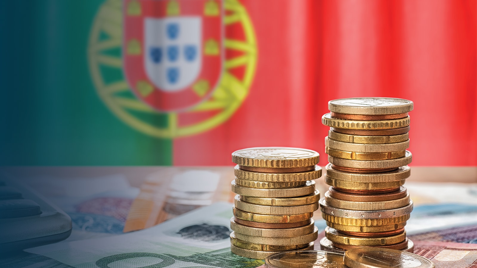 Coins and banknotes on a table with the Portuguese flag in the background